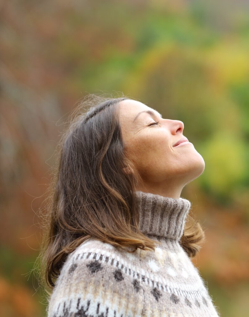 Side view portrait of a middle aged woman breathing fresh air in a forest